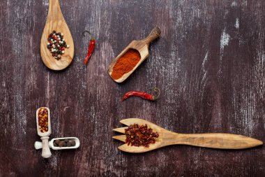 Koyu kahverengi zemin üzerine tahta kaşıklar içinde çeşitli baharatlar. Farklı