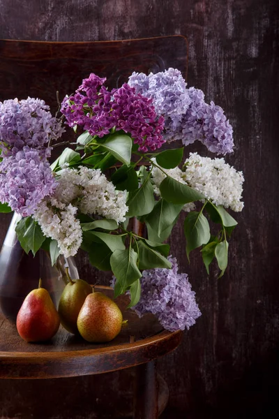 Bouquet of lilac flowers and three pears on old vintage chair. — Stock Photo, Image