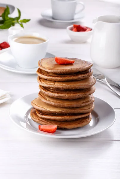 Stapel chocolade pannenkoeken met aardbeien op witte houten ta — Stockfoto