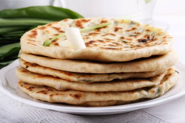 Khychiny geleneksel beyaz gözleme peynir ve otlar ile dolu. Beyaz peynir ve yabani sarımsak ile düz ekmek dolması.