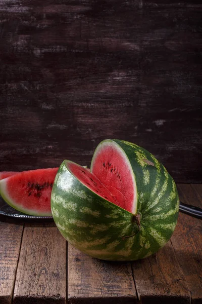 Gesneden rijpe watermeloen op bruin houten tafel. — Stockfoto