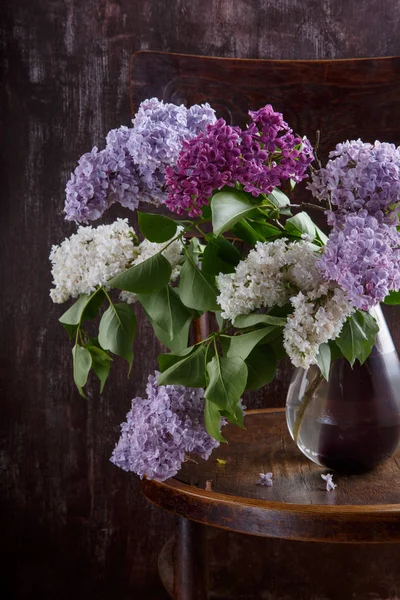 Bouquet of lilac flowers on old vintage chair.  Still life on da — Stock Photo, Image