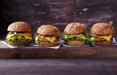 Ahşap masa üzerinde dört ev yapımı hamburger. 