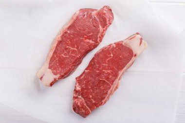 Çiğ dana striploin biftek. Beyaz masada iki şerit bel biftek.