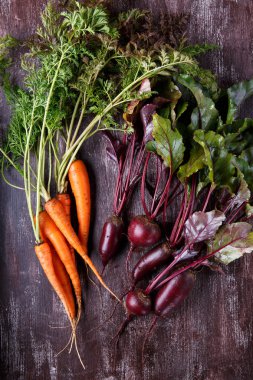 Koyu arka planda yeşil yaprakları ile taze havuç ve pancar.