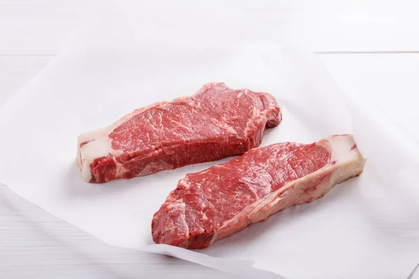 Raw beef striploin steak. Two strip loin steaks on white table. — Stock Photo, Image