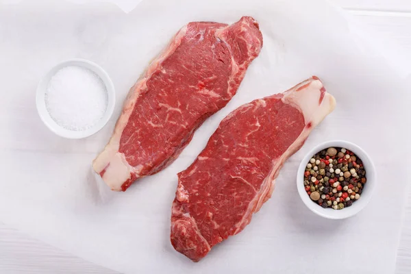 Carne de res cruda con bistec. Dos filetes de lomo en la mesa blanca . — Foto de Stock