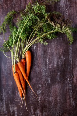 Koyu arka plan üzerinde yeşil yaprakları ile taze havuç demet.