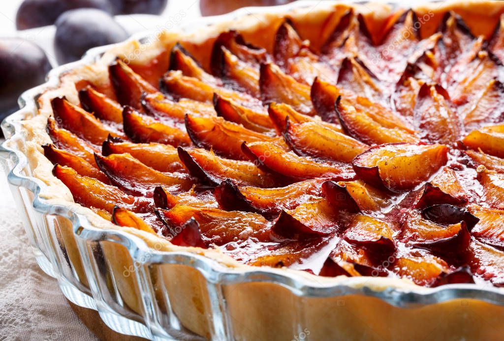 Homemade plum pie. Fruit tart on white table. 