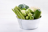 Sortiment zelené zeleniny na bílém stole. Brokolice, květák