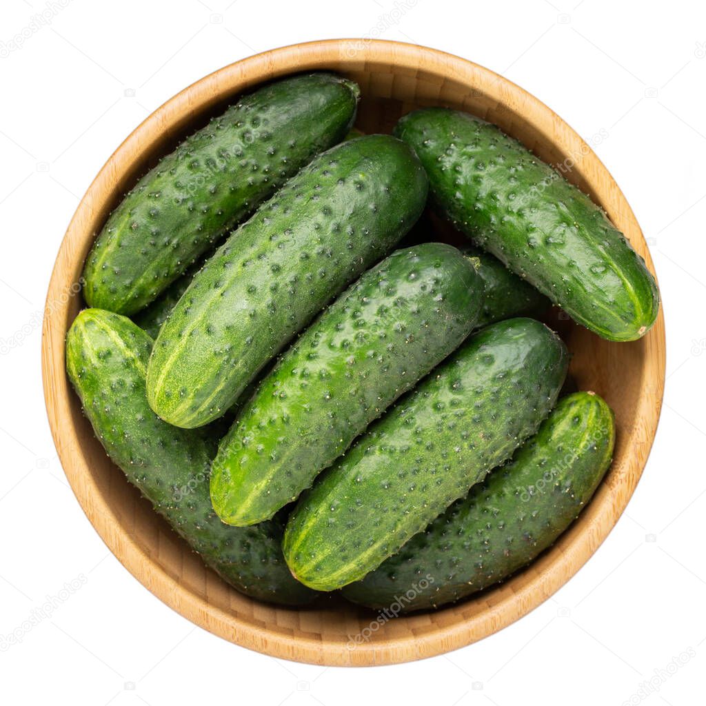Whole cucumbers in wooden bowl isolated on white. Top view.