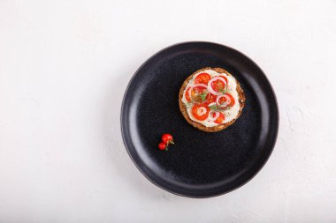 Domatesli ve soğanlı tam tahıllı sandviç, siyah tabakta karabiberle tatlandırılmış. Beyaz arka planda açık vejetaryen sandviçi. Üst Manzara. Vejetaryen yemeği. Sağlıklı, temiz yeme konsepti. Boşluğu kopyala.