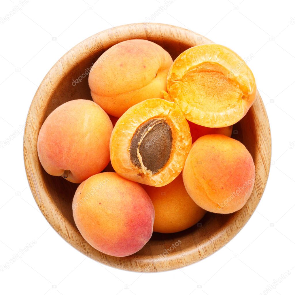 Fresh ripe apricots in wooden bowl isolated on a white background.  Top view, close-up.
