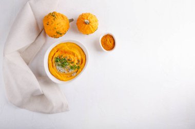 Kabak çekirdeği ve maydanozla servis edilen baharatlı balkabağı çorbası. Beyaz masada sonbahar çorbası ile kase. Üst Manzara. Boşluğu kopyala.