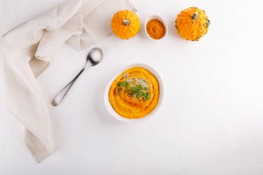 Kabak çekirdeği ve maydanozla servis edilen baharatlı balkabağı çorbası. Beyaz masada sonbahar çorbası ile kase. Üst Manzara. Boşluğu kopyala.