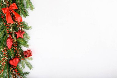 Kırmızı süslemeler ve beyaz arka planda kırmızı böğürtlenlerle süslenmiş ladin dalları. Noel köknar ağacı. Üst Manzara. Uzayı kopyala Noel veya Yeni Yıl arkaplanı.