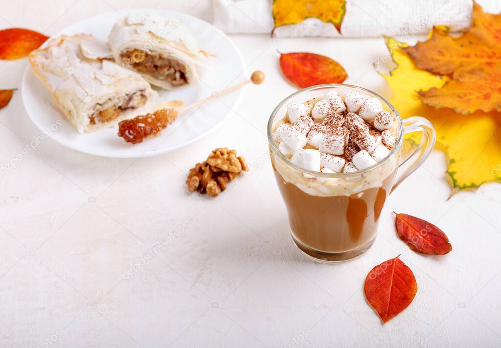 Autumn composition with cup of hot drink, delicious apple strudel   and colorful fall leaves on white background. Copy space. Autumn mood, fall season concept.