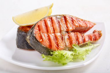 Limonlu ızgara kırmızı somon bifteği ve beyaz tabakta marul. Somon balığı, somon balığı veya Oncorhynchus nerka.