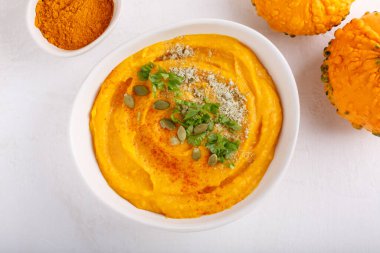 Kabak çekirdeği ve maydanozla servis edilen baharatlı balkabağı çorbası. Beyaz masada sonbahar çorbası ile kase. Üst Manzara. Boşluğu kopyala.