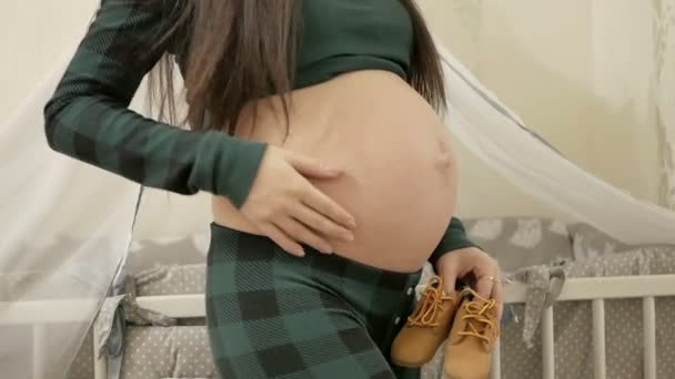 Beautiful Pregnant woman Playing with kid bootees. — Stock Video