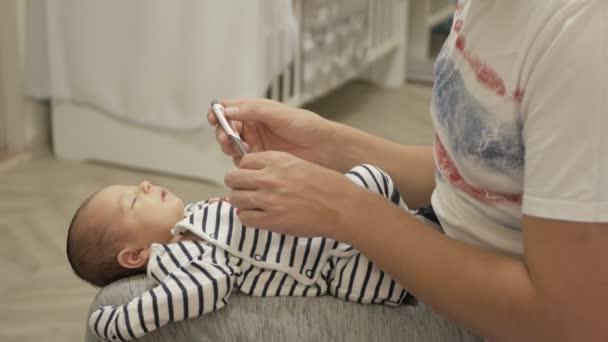 Père vérifiant la température d'un nouveau-né — Video