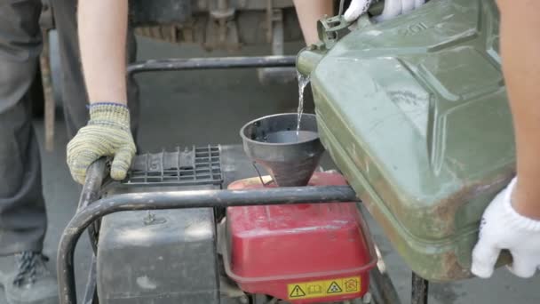 Les hommes versent l'essence de la boîte dans le générateur . — Video