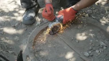 Adam dairesel testere ile çalışıyor. Sıcak metalin kıvılcımları.