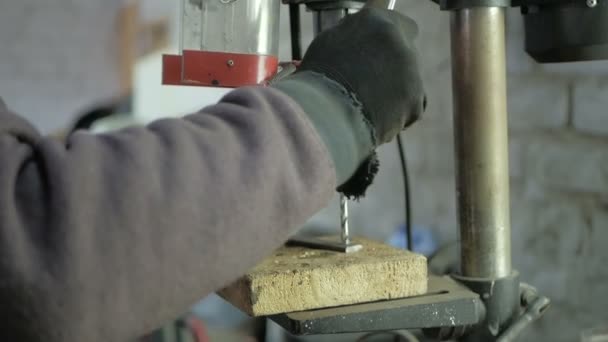 Человек специализируется на сверлении отверстий на буровой установке в металлической детали — стоковое видео