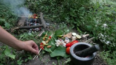 Ormanda bir kamp ateşinde deniz ürünleri kebabı pişirmek.
