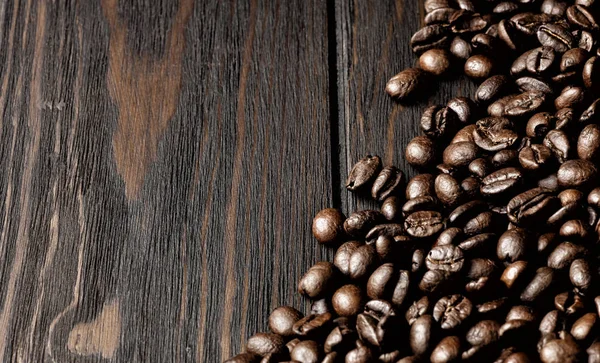 Textura de granos de café tostados sobre mesa de madera, muchos granos, — Foto de Stock