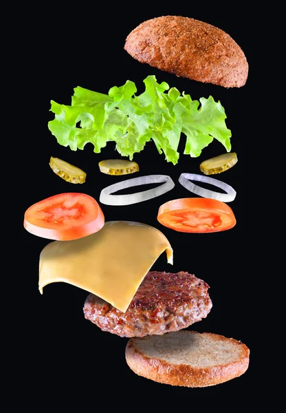 Leckere leckere Hamburger mit fliegenden Zutaten isoliert auf schwarzem Hintergrund. Burger-Teile fliegen in der Luft. Schwimmender Burger — Stockfoto