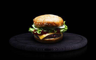 Peynirli hamburger ızgara et, peynir, domates, salata ve soğan halkaları ile. Siyah bir arka plan üzerinde siyah ahşap tahta üzerinde lezzetli taze ev yapımı Hamburger Close-up