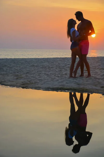 Una pareja amorosa mirando el atardecer en la playa — Foto de Stock