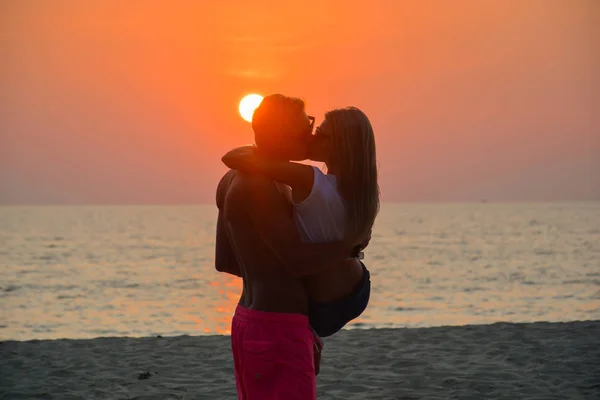 Una pareja amorosa mirando el atardecer en la playa — Foto de Stock