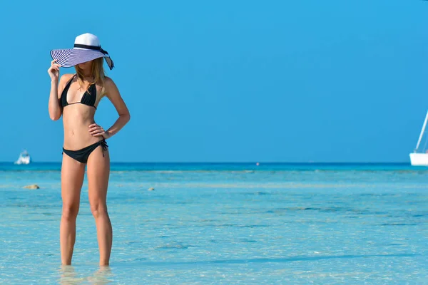 Fit girl on a tropical beach with hat. Sexy bikini body woman on paradise tropical beach. Beautiful fit body girl on travel vacation. Banner crop for copy space. Stock Image