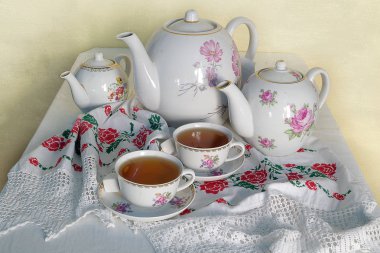 Natürmort işlemeli el yapımı çiçek desenli havlu üzerinde çay Çaydanlık ve bardak.