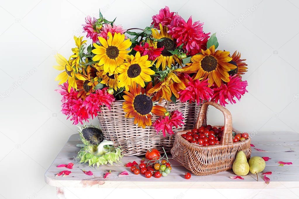 Still life with sunflowers and dahlias and vegetables and fruits.