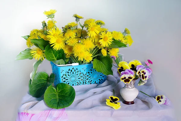 Beautiful bouquet of viola, dandelions and purple flowers in a vase isolated on a light background