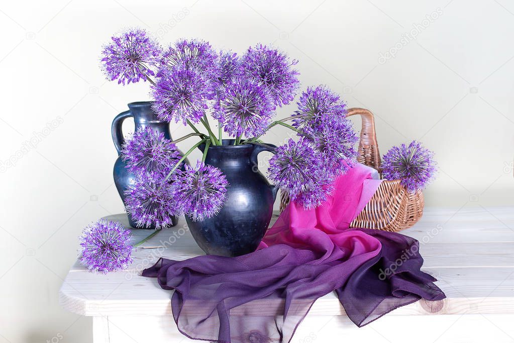 Still life with purple flowers of onions in a vase on a white background