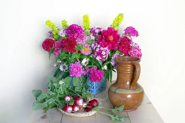 Still life with carnation flowers in a vase and red radish on a saucer