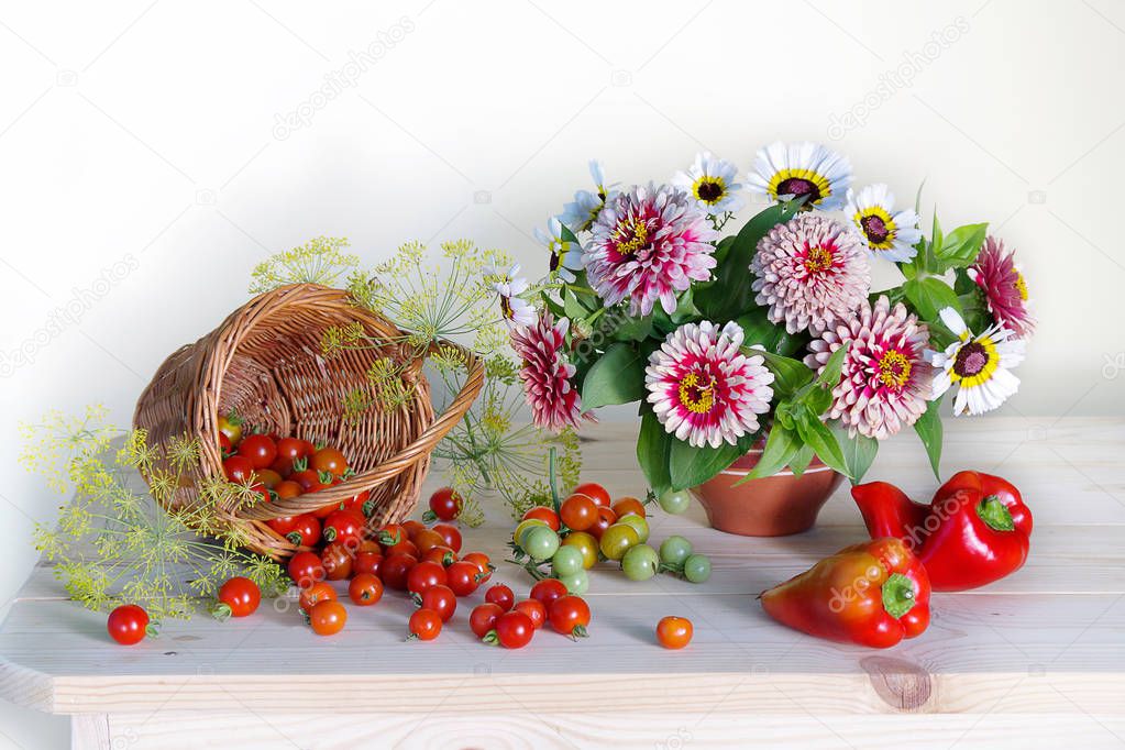 The composition of flowers in a vase, cherry tomatoes, red peppers on the table on a neutral background