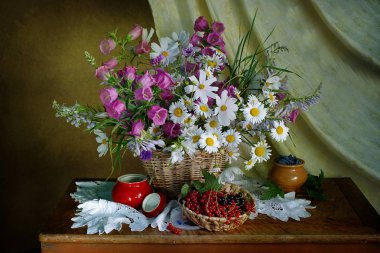 Sepet içinde çiçekler, kahverengi bir arka plan üzerinde bir masada olgun berry ile natürmort