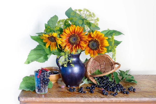 Beautiful bouquet of sunflowers in a vase and black currant berries. Still life with flowers and berries.