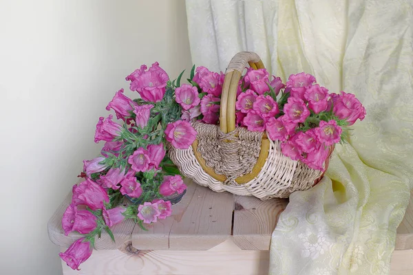 Beyaz bir arka plan masada yatan bir sepette pembe çan buket