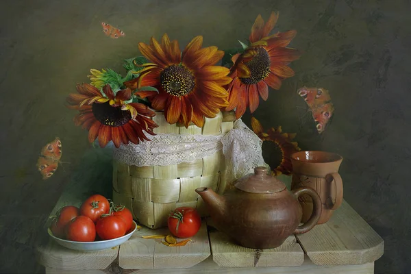 Still life with large sunflowers in a vase and ripe red volumes on a plate on a brown background