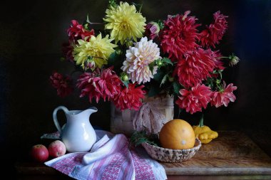 Masa üzerinde bir sepet ve balkabakları bir buket dahlias ile hala hayat