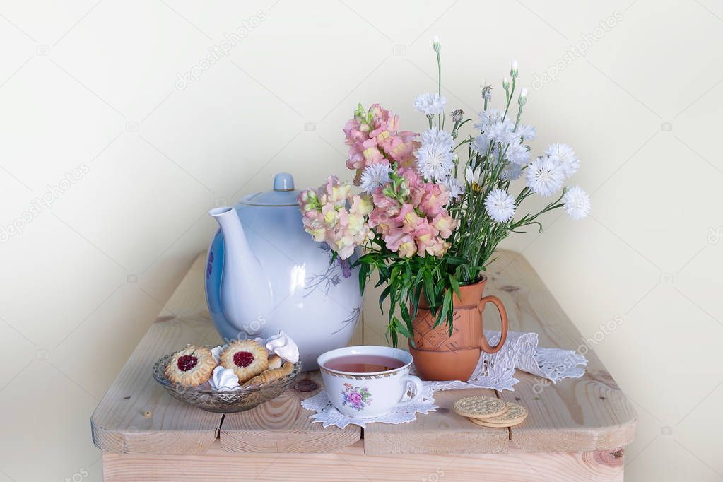 Teapot and a Cup of tea with a bouquet of pink-yellow and white flowers