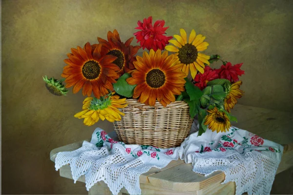 Still life with sunflowers in a basket with embroidered flowers on a towel