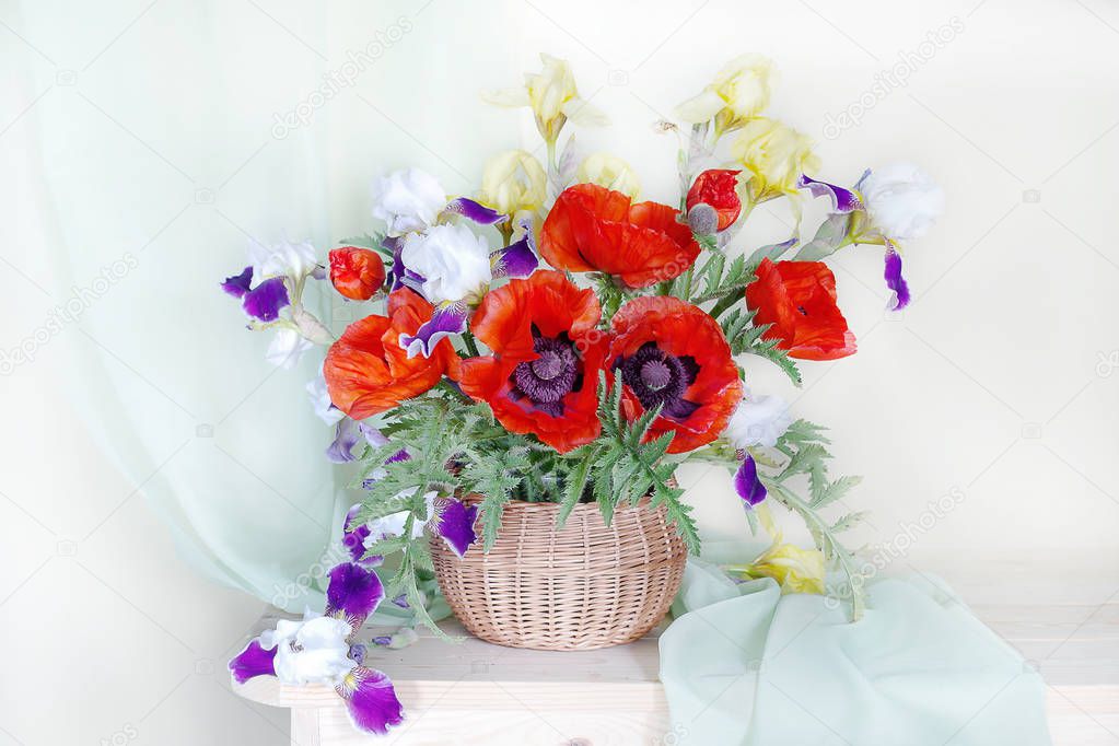 Large red poppies and irises in a bouquet on a white background.Beautiful bouquet of poppies,irises in a basket.