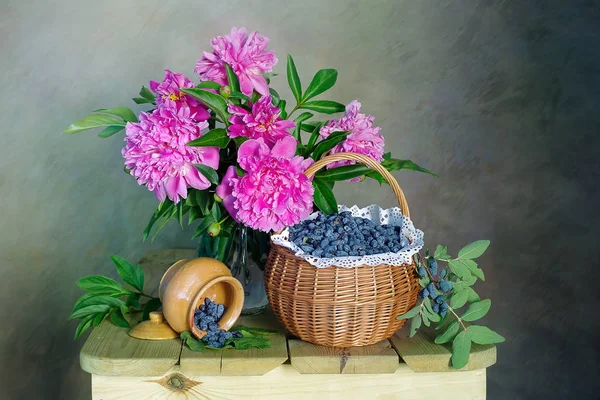 A bouquet of beautiful pink peonies and a basket of berries .Still life of pink peonies.